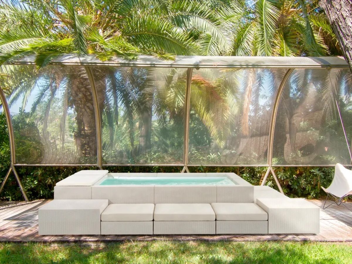 Piscine hors sol Playa de ton clair avec ses éléments de banquette modulaire sous un abri pour se protéger de la pluie