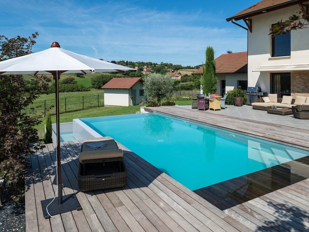 Piscine à débordement sur deux côtés, plage et margelles en bois