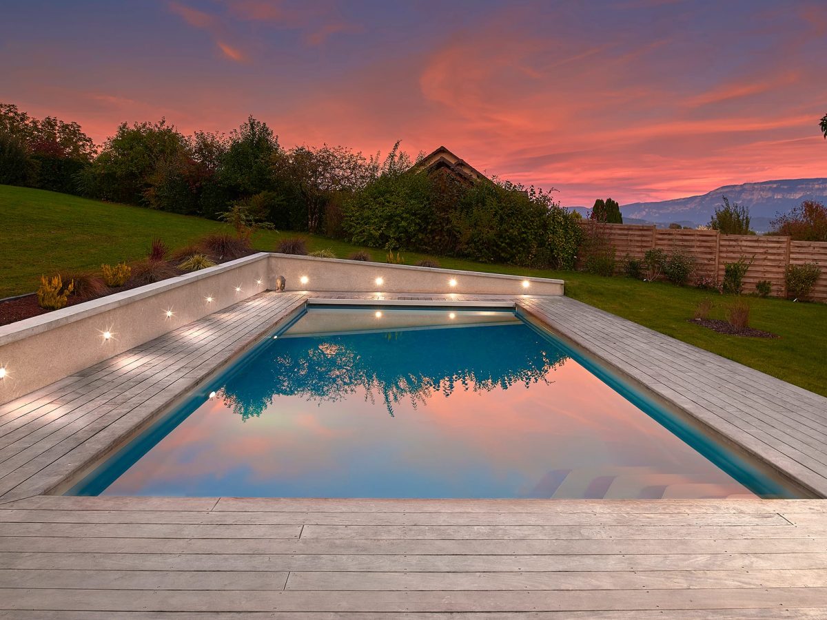 Piscine extérieure de 11 x 4.5 m avec spot leds et plage en bois exotique